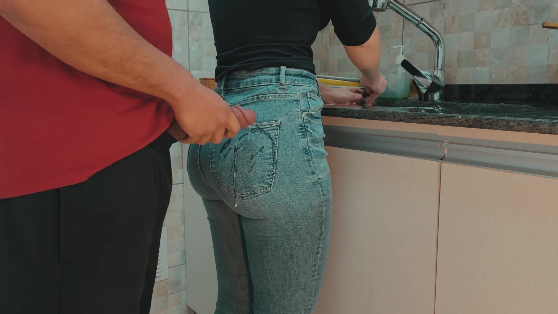 Una mujer delgada y adúltera que lava platos deja que su jefe toque sus jeans mientras ella lava los platos.